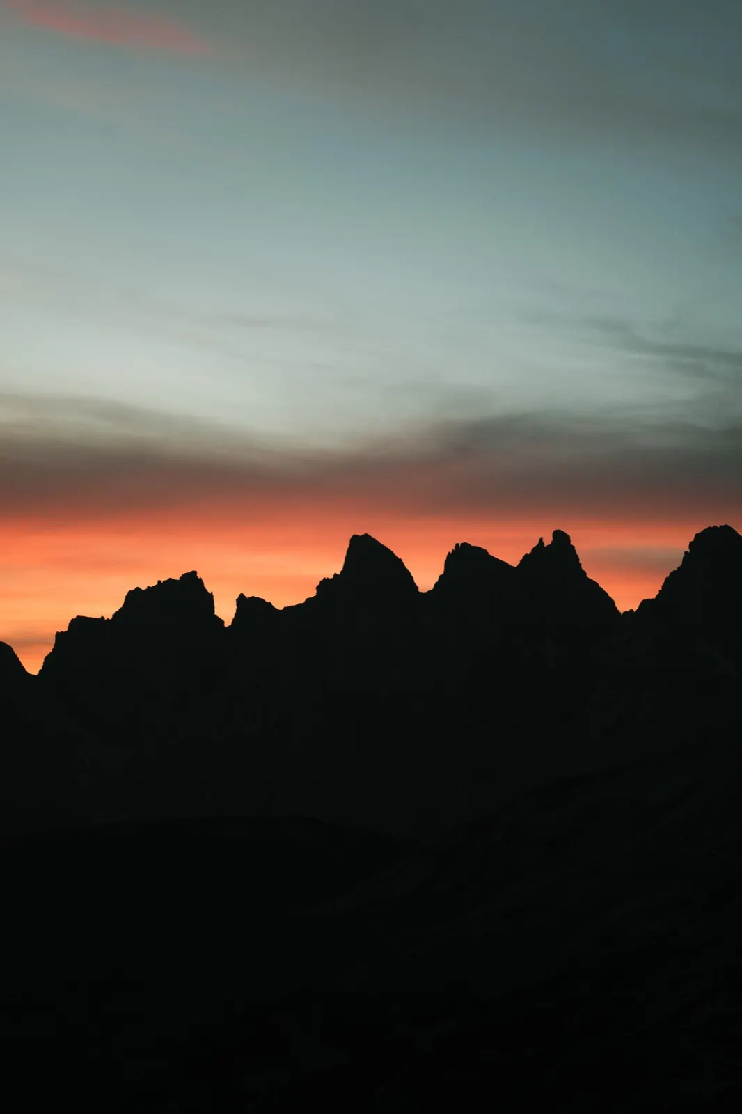 Orange-pink sky with the dark silhouette of a mountain ridge