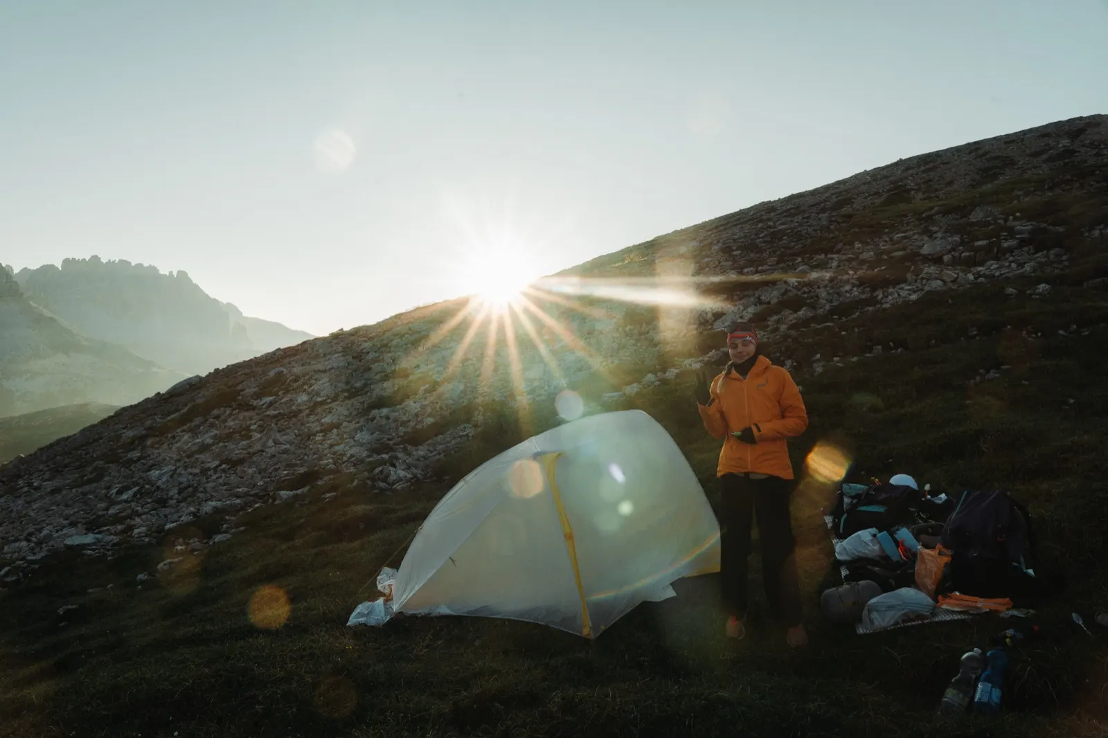 Morning at the tent with the sun rising from behind the hill
