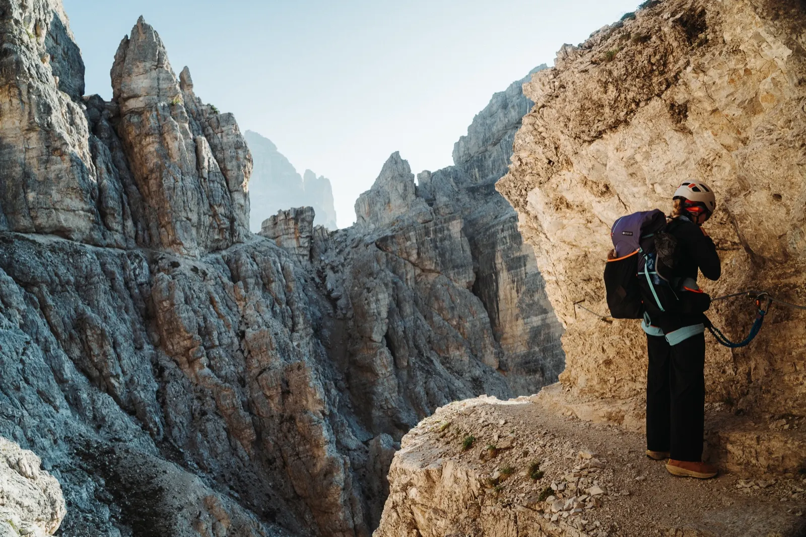 Hiker on a narrow exposed section with via ferrata protection in the Dolomites