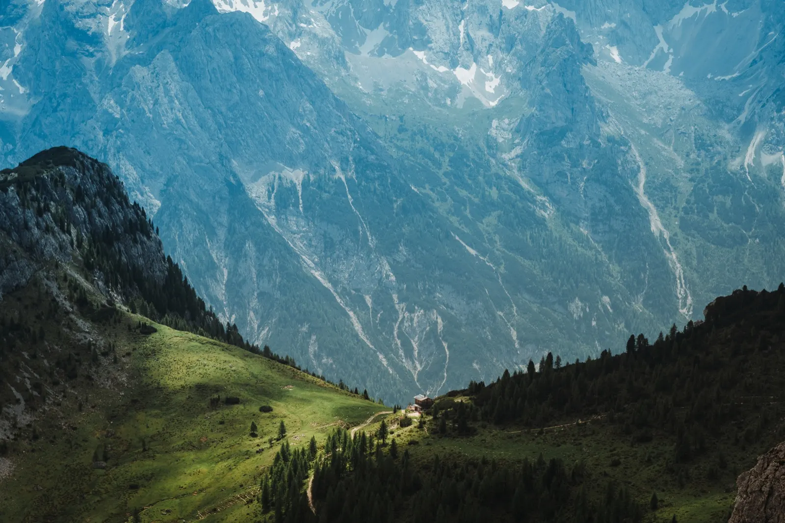 Panoramic view into a green valley surrounded by steep Dolomite walls