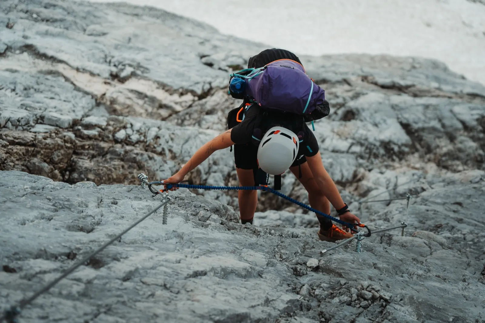 Climbing with the help of a steel cable on steep rocky terrain.