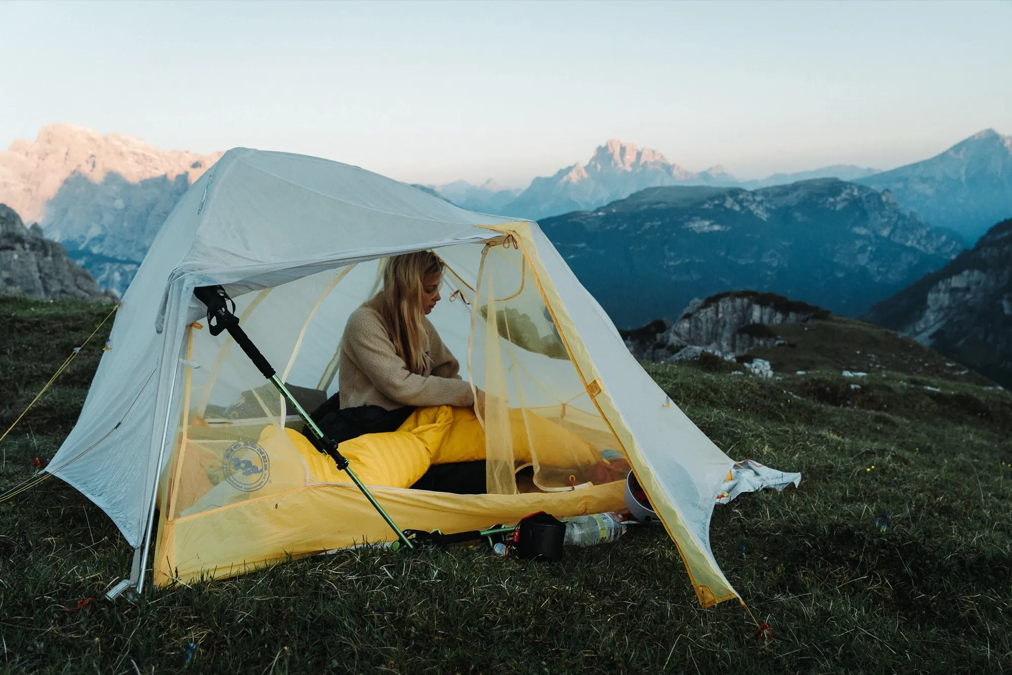 Hiker sitting in the open door of a Tiger Wall UL2 with mountains behind