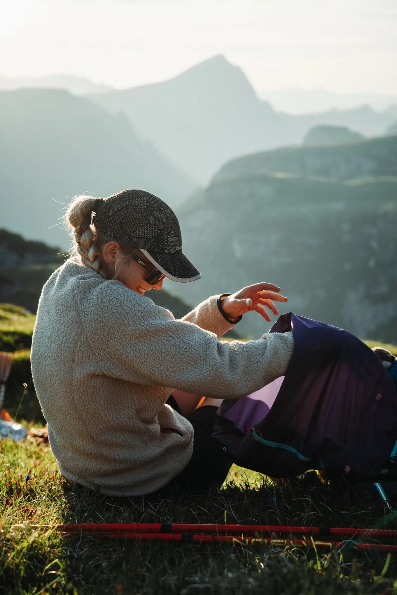 Hiker adjusting a purple Gorilla 50 backpack on a mountain trail