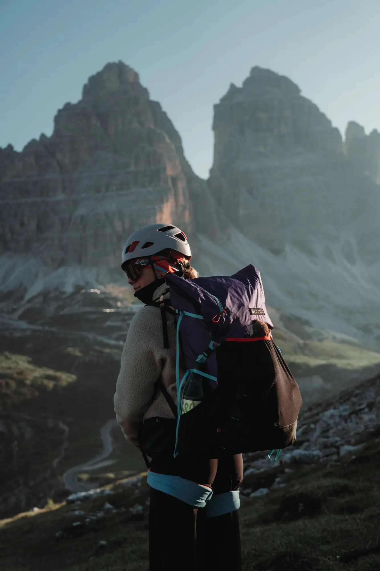 Hiker lifting a purple Gorilla 50 backpack in misty mountain light