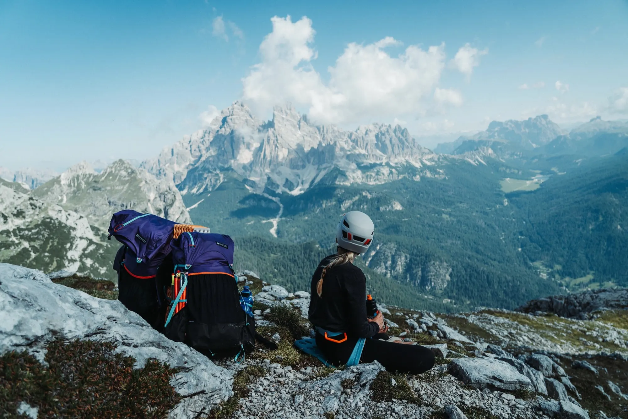 Two hikers resting on rocks with a Gorilla 50 backpack and Dolomite peaks behind