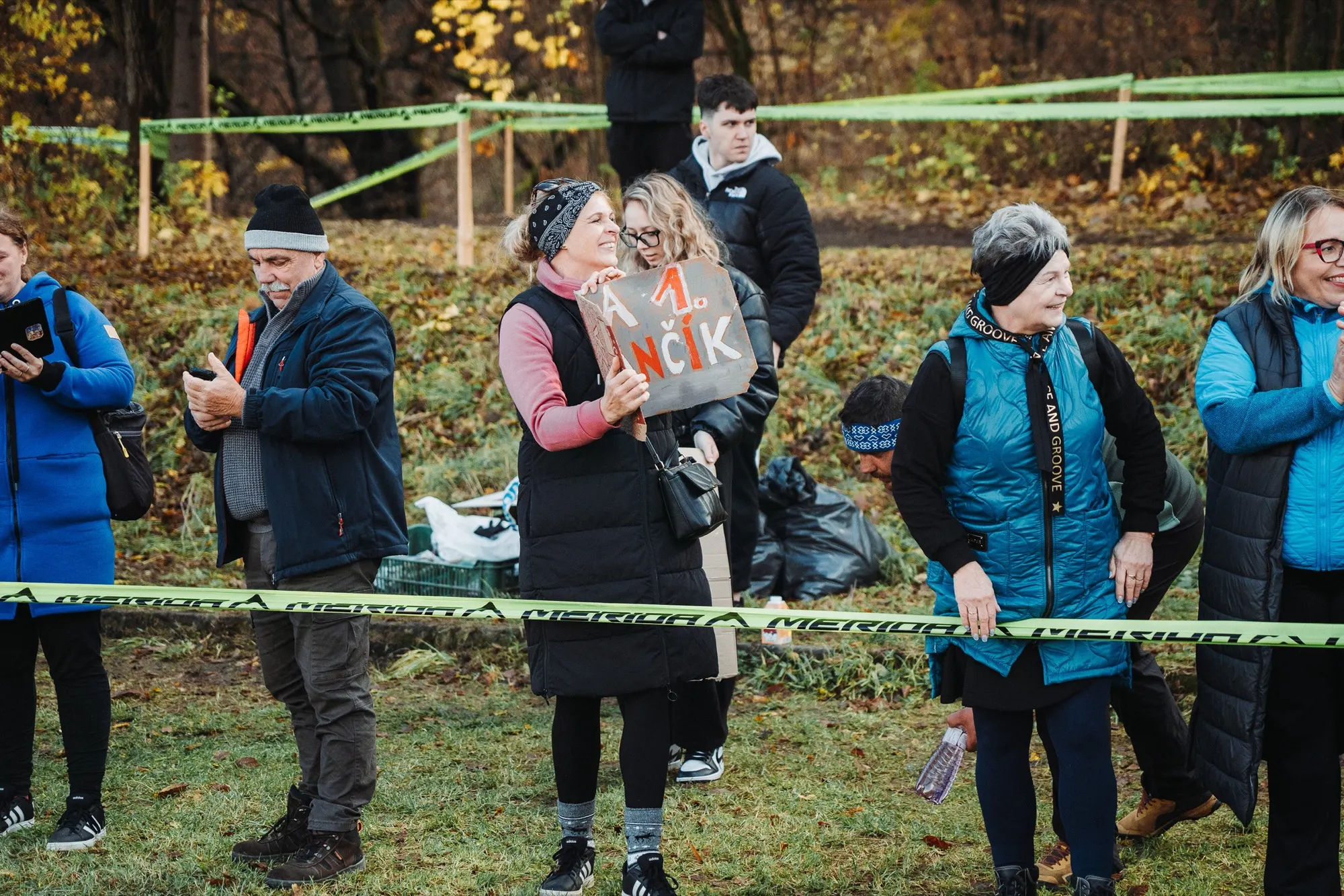 Spectators and staff standing behind course tape in the forest