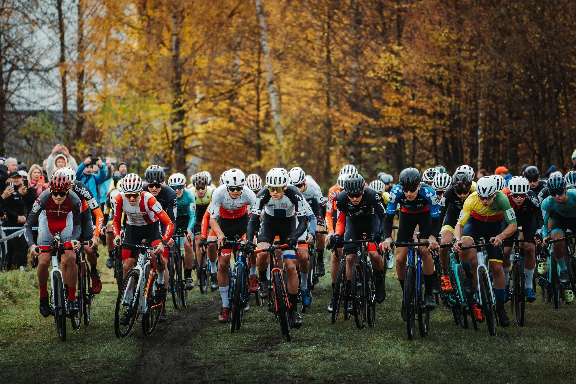 Large field of riders at the start of the cyclo-cross race on autumn grass