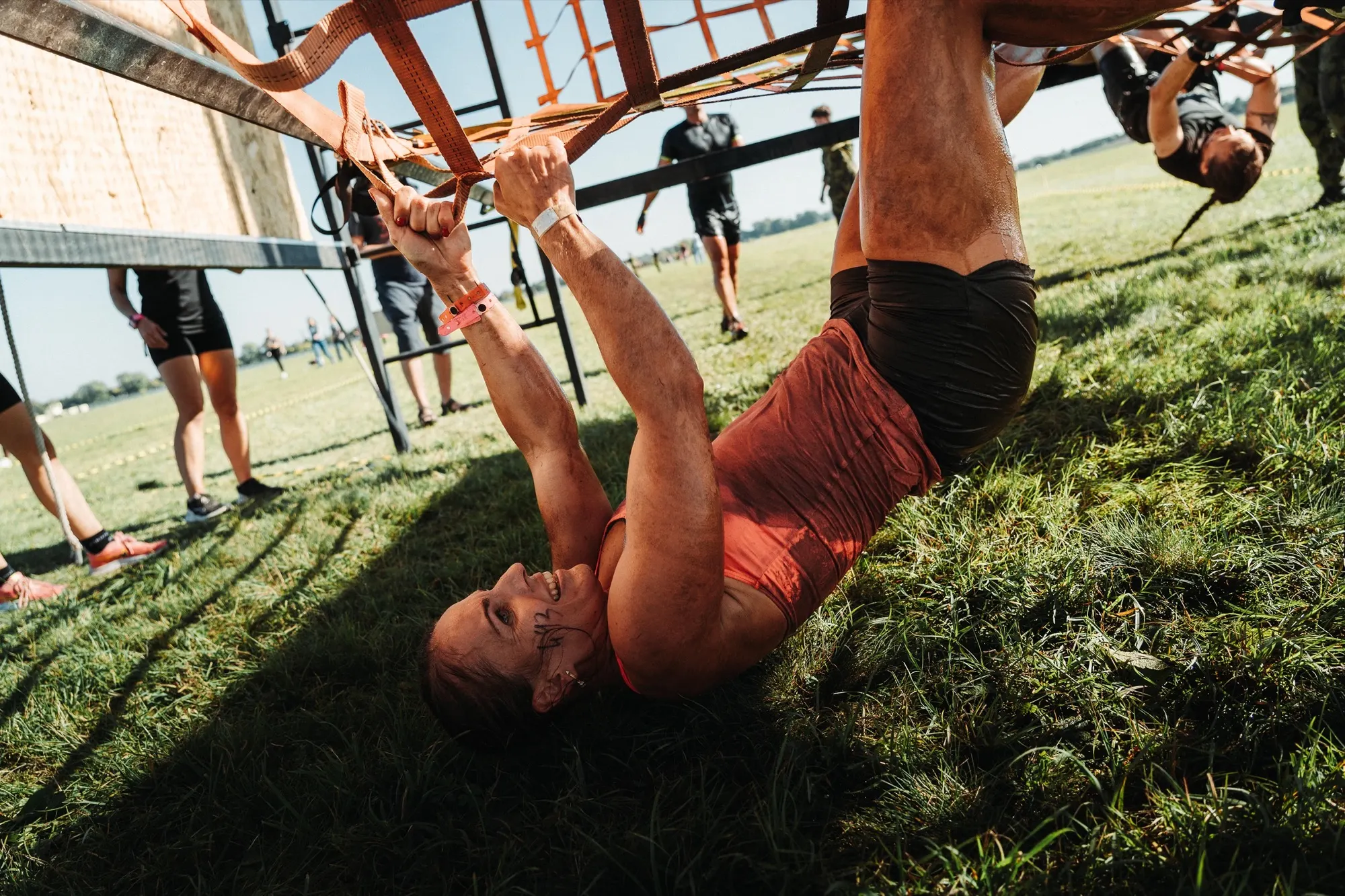Competitor hanging upside down from an obstacle bar