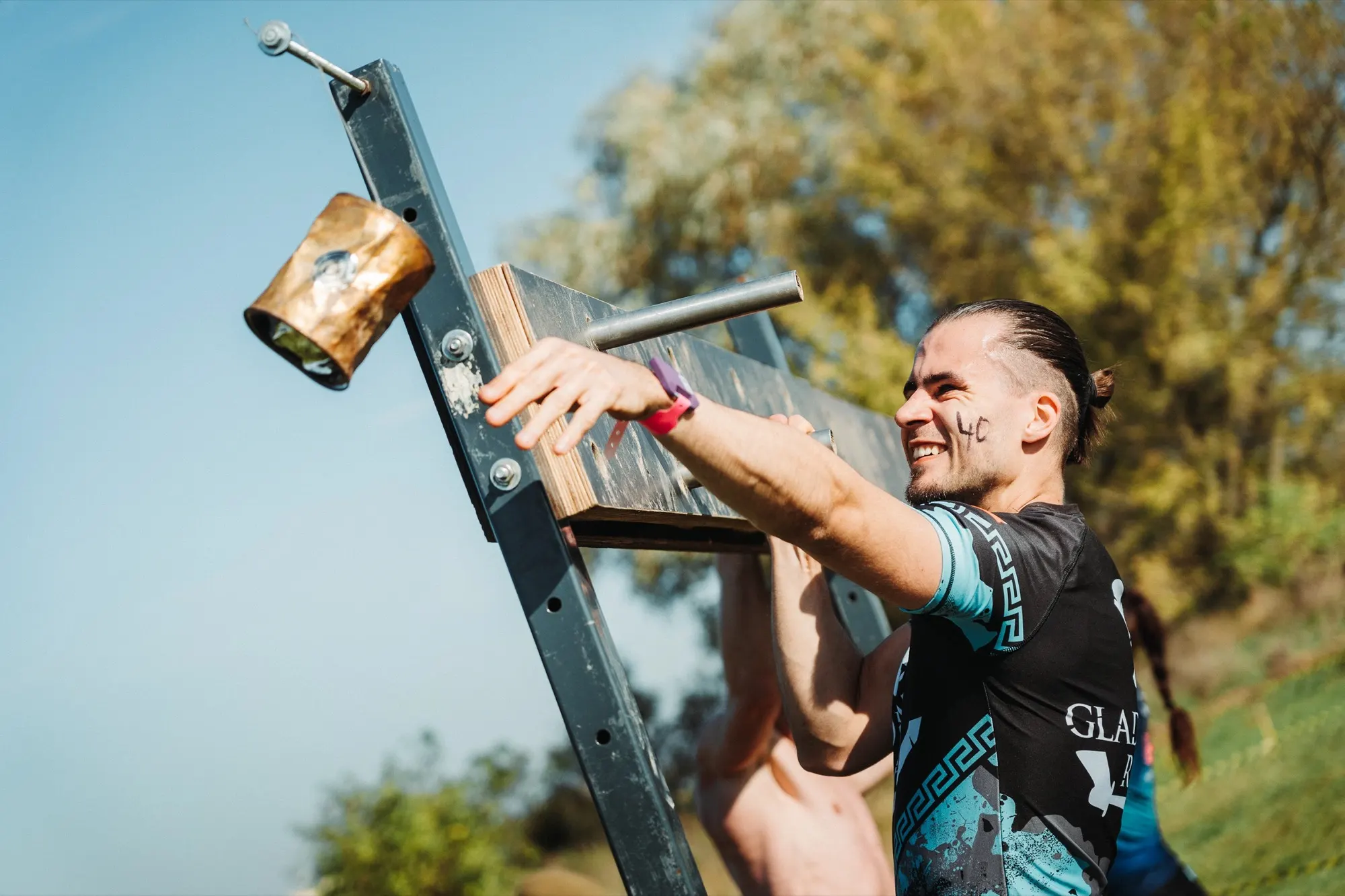 Competitor climbing a metal frame obstacle under a blue sky